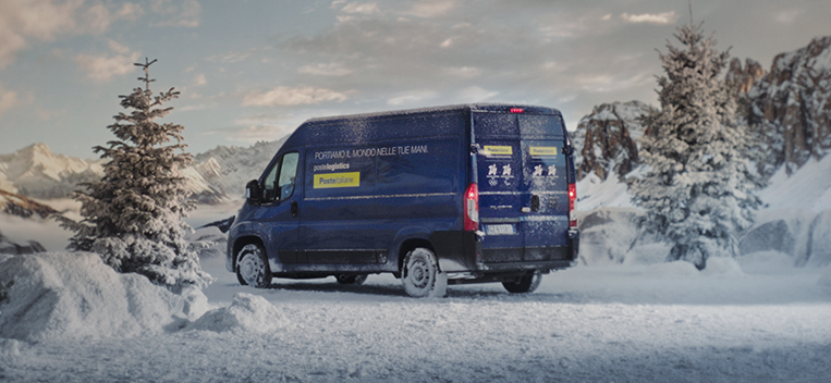 Furgoncino blu Postelogistics su sfondo innevato